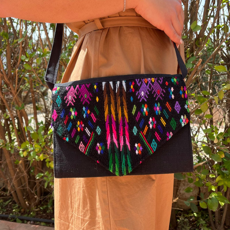 Woman wearing a black crossbody bag with vibrant multicolor embroidered patterns outdoors
