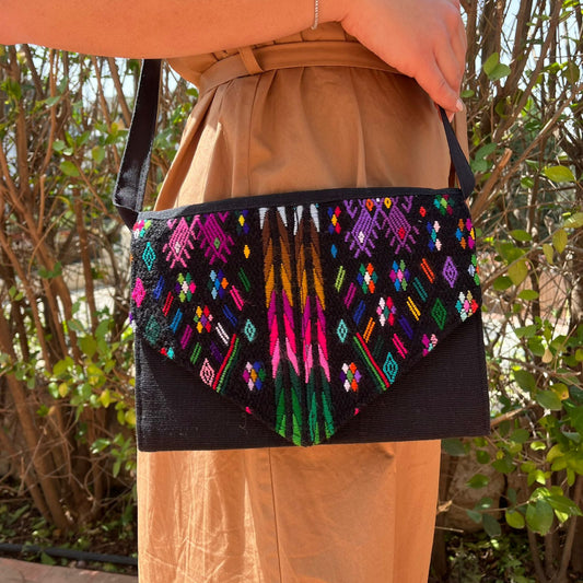Woman wearing a black crossbody bag with vibrant multicolor embroidered patterns outdoors