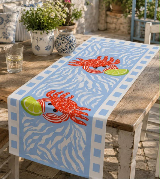 Blue and white coastal table runner with red lobster and green lime design on a rustic wooden dining table