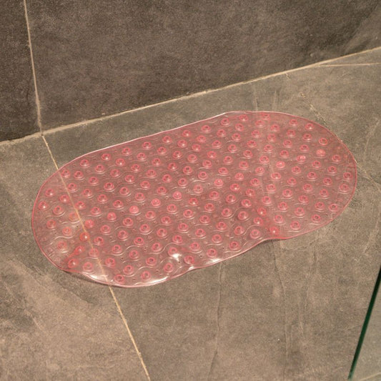 Soft pink anti-slip capsule rubber shower mat on gray tiled bathroom floor
