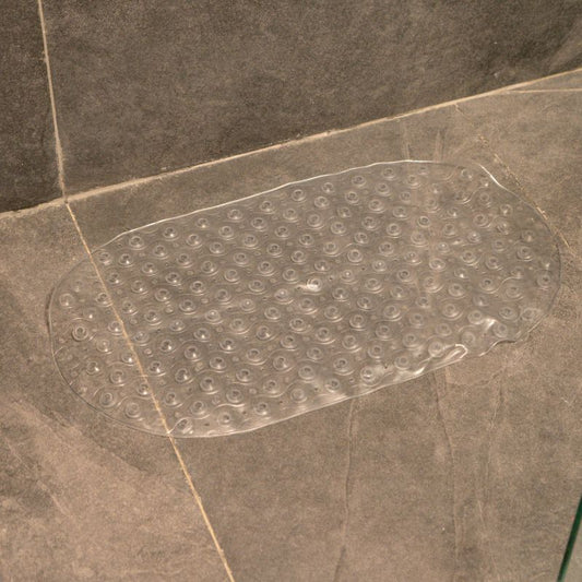 Transparent anti-slip capsule rubber shower mat on gray tiled bathroom floor