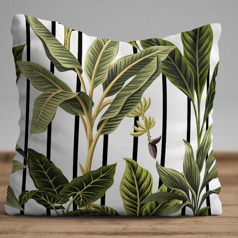 Tropical leaf cushion cover with green botanical design over black and white striped background