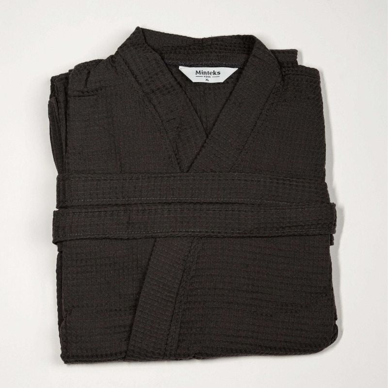 Grey waffle cotton bathrobe with belt and front pockets worn by woman on a balcony