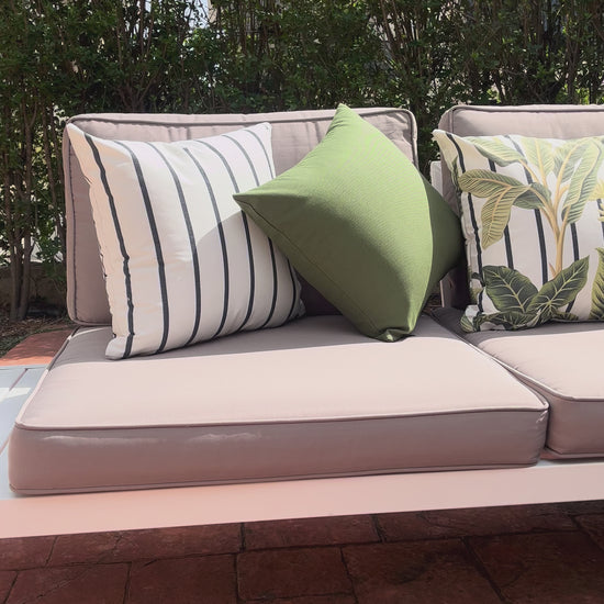 White cushion with green tropical leaves in a botanical pattern design