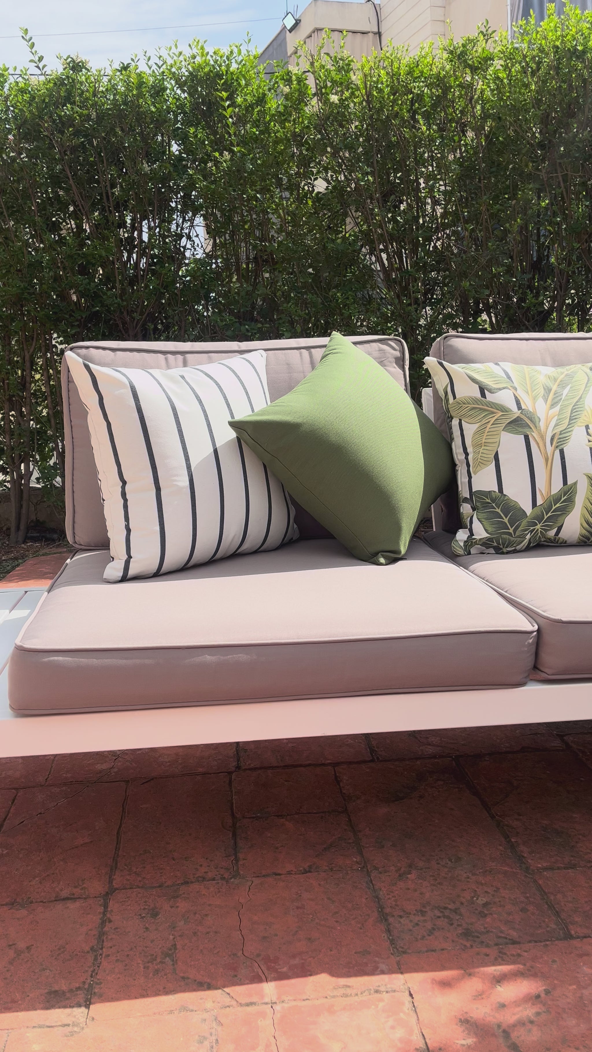 White cushion with green tropical leaves in a botanical pattern design