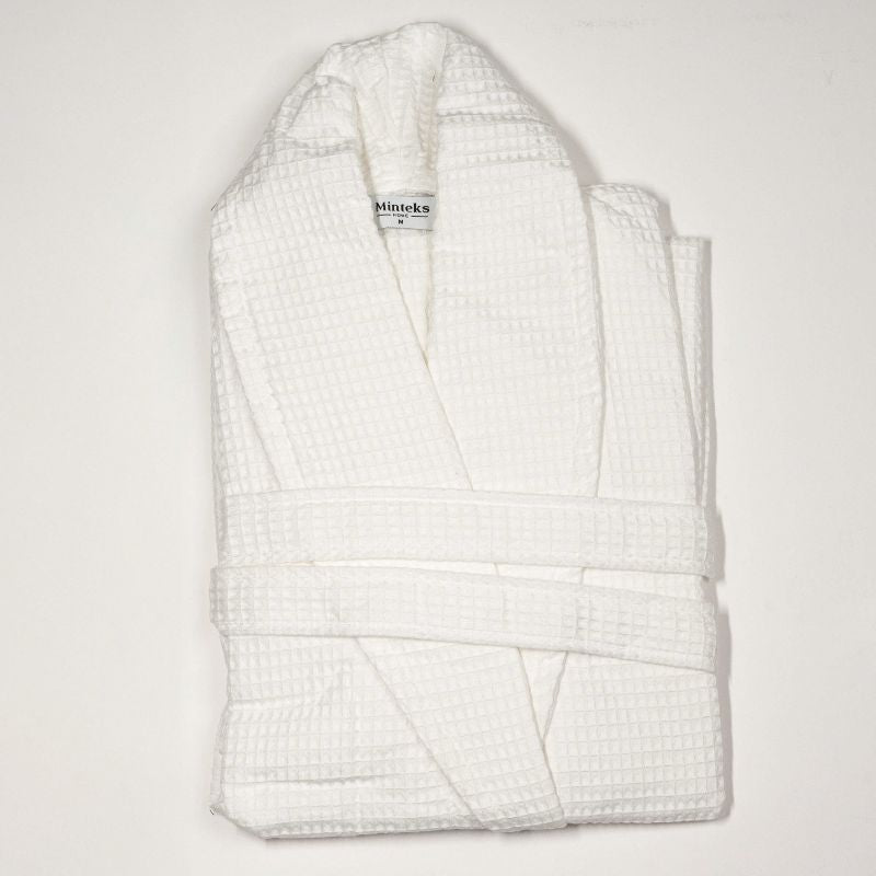 White waffle cotton bathrobe with belt and front pockets worn by woman on a balcony